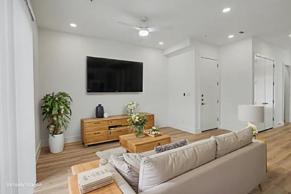Living room with wood flooring, ceiling fan, and a wall-mounted television