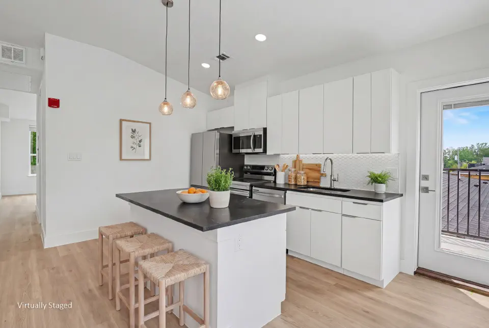 Kitchen with white cabinetry, black countertops, island seating, and balcony access