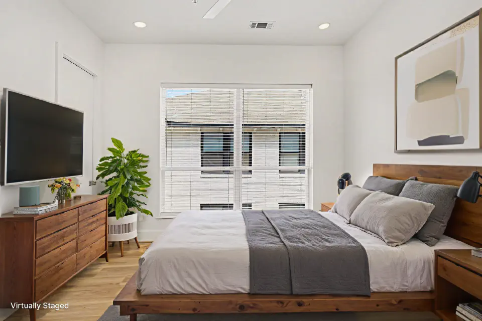 Bedroom with a large window, wood furniture, and wall-mounted television