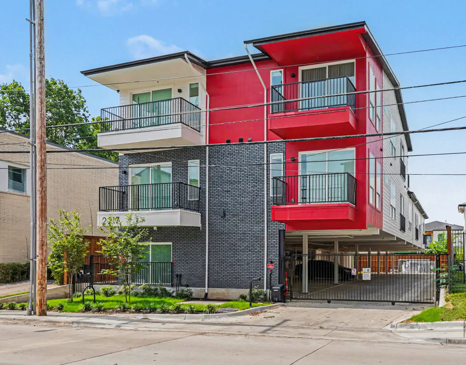 Street-level view of the red, white, and charcoal exterior with private balconies
