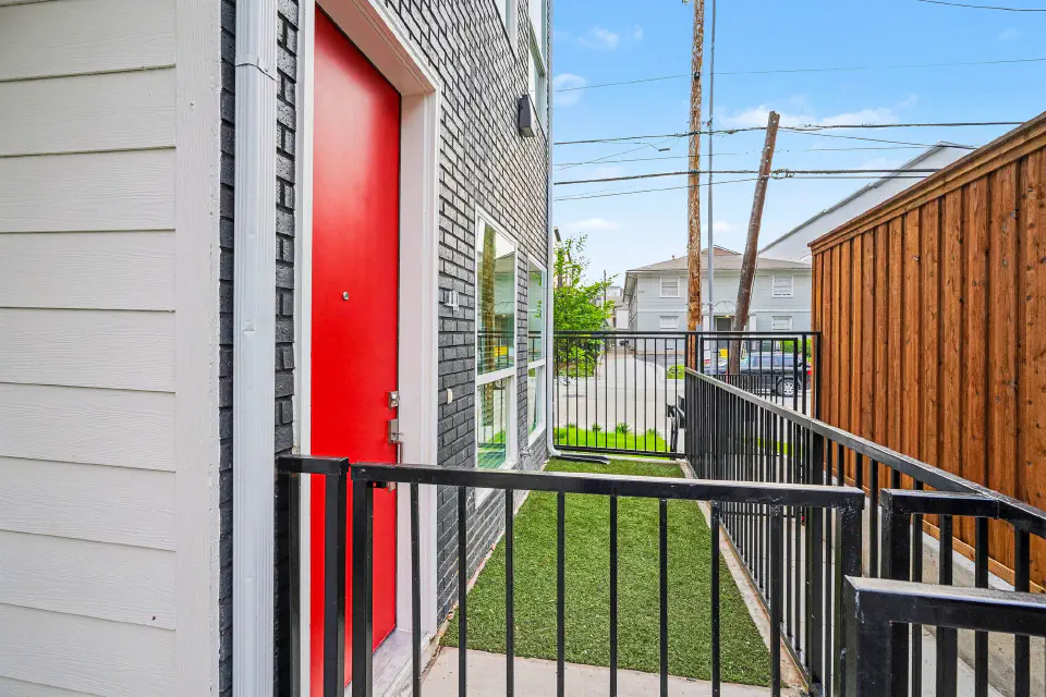 Private ground-floor entrance with a red door and fenced patio