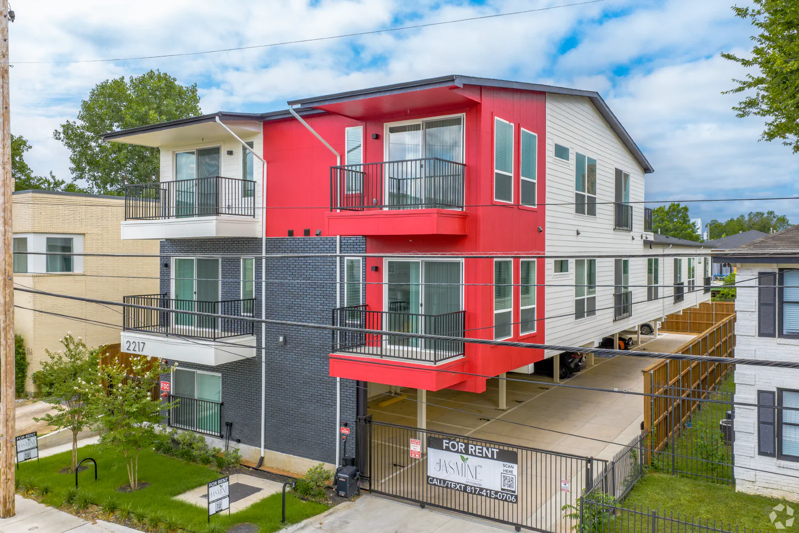 Exterior of Jasmine@Fitzhugh with red and charcoal accents, private balconies, and covered parking