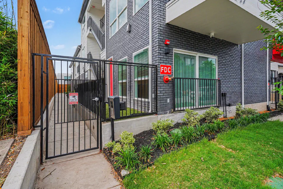 Controlled-access pedestrian gate beside the landscaped front lawn