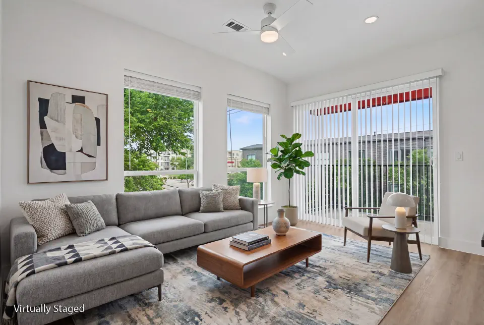 Corner living room with oversized windows, balcony access, and a ceiling fan