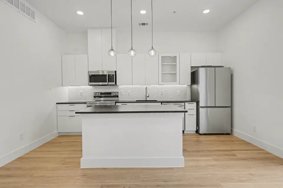 Open kitchen with island, stainless steel appliances, and pendant lighting