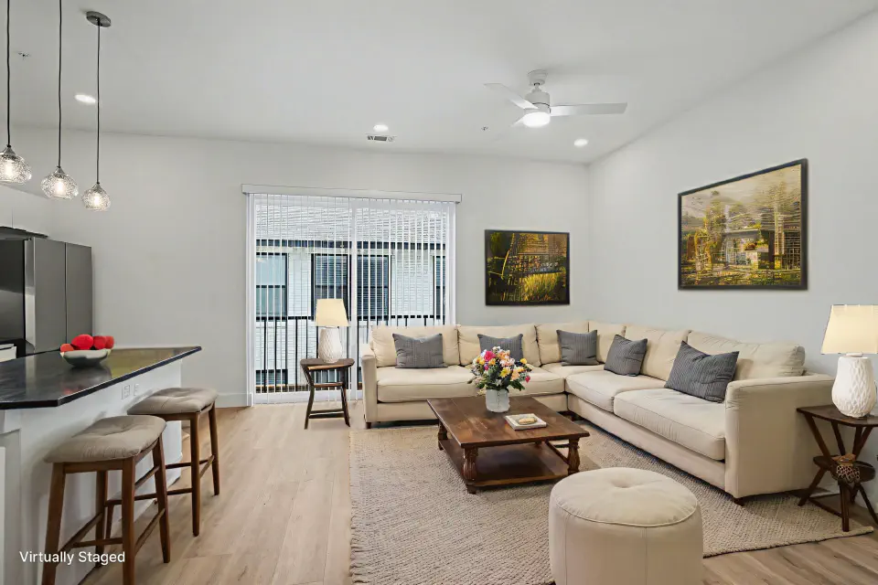 Open-plan living room with kitchen island seating and balcony access