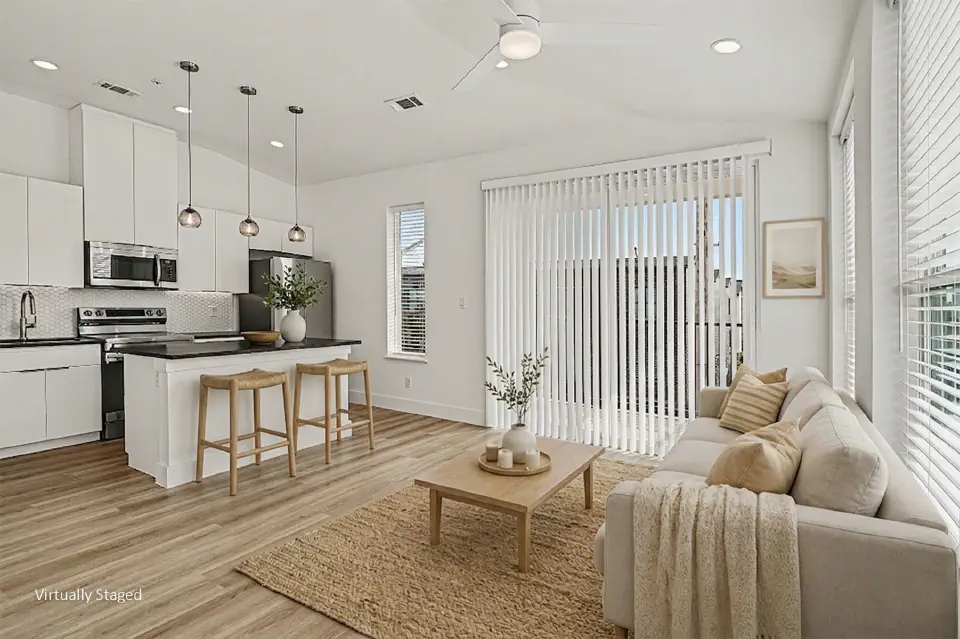 Bright living room and kitchen with island seating and windows on two sides