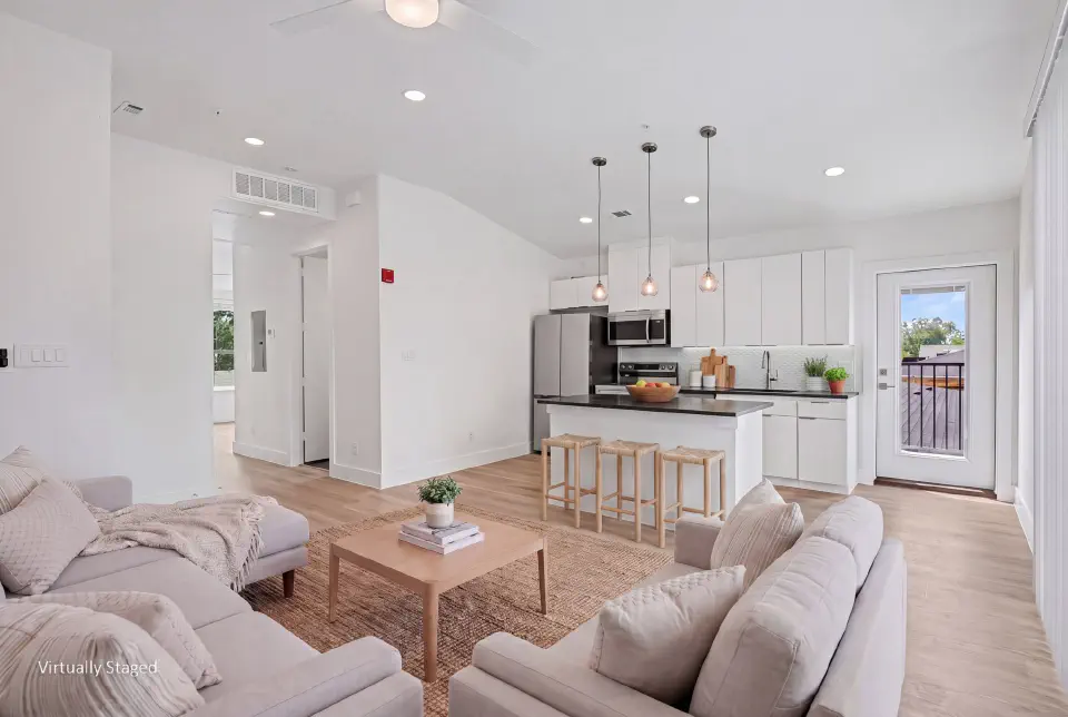 Open living room and kitchen with island seating and balcony access