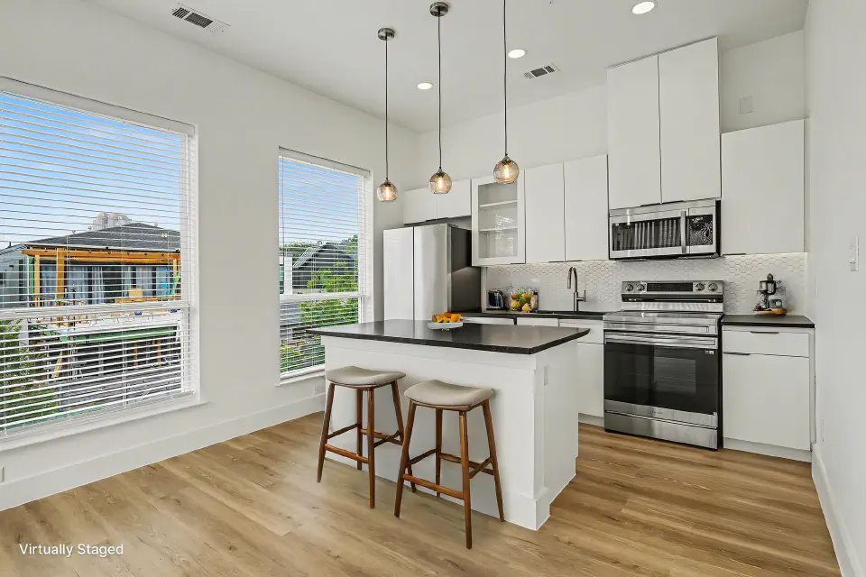 Kitchen with tall white cabinetry, stainless steel appliances, and island seating