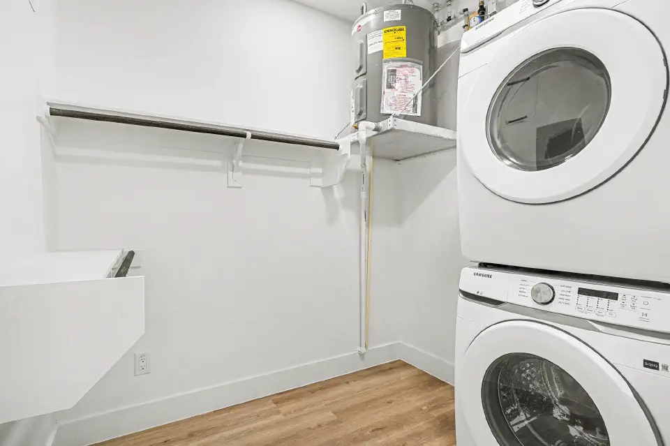 Walk-in closet with built-in shelving and a stacked in-unit washer and dryer
